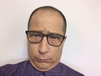 Portrait of young man wearing eyeglasses against white background