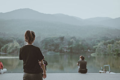 Back view point of young woman standing near the lake and look at faraway , hope and dream concept