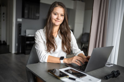 Portrait of young woman using laptop at table