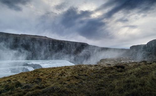 View of waterfall against cloudy sky