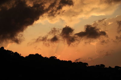 Low angle view of silhouette trees against dramatic sky