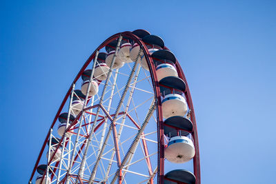 Low angle view of ferris wheel against clear blue sky