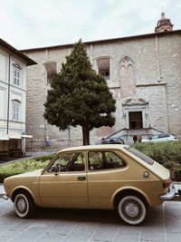 Car on street by buildings against sky