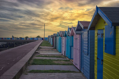 Footpath amidst buildings against sky during sunset