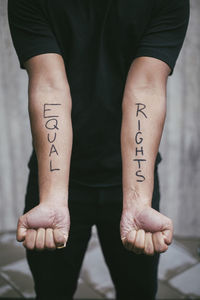 Midsection of male protestor showing equal rights written on hand