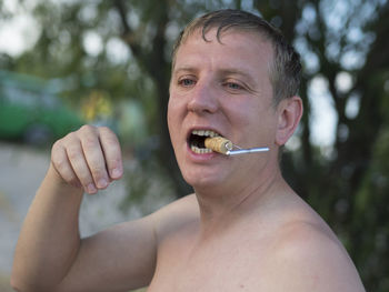 Shirtless man holding cork in mouth