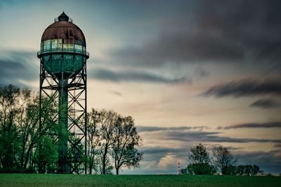 Low angle view of water tower on land against sky at sunset