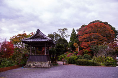 Gazebo amidst trees and building against sky