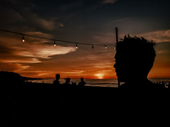 Silhouette people on beach against sky during sunset