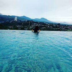 Woman in sea against mountain