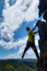 Rear view of man standing on rock against sky