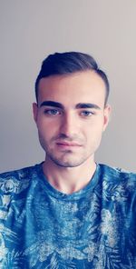 Portrait of young man standing against gray background