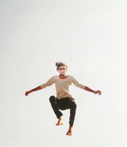 Portrait of young man jumping against sky