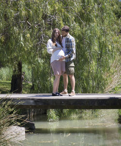 Full length of couple standing on bridge by trees