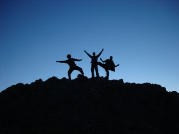 Low angle view of silhouette people against clear blue sky