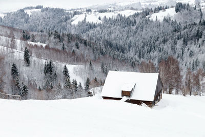 Snow covered landscape and houses on field