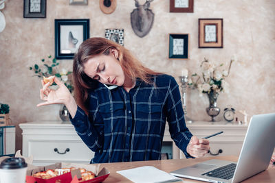 Young woman using mobile phone at table