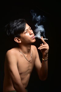 Beautiful young woman smoking over black background