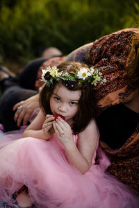 Young girl in flower crown posing with strawberry