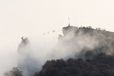 Suspension bridge people. silhouettes of people walking across the bridge through the clouds.