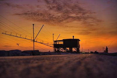 Silhouette built structure by sea against sky during sunset