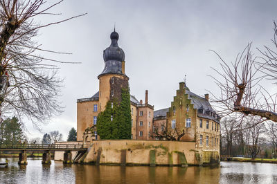 View of buildings by river against sky