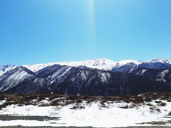 Scenic view of snowcapped mountains against clear blue sky