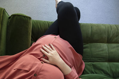 Midsection of woman sitting on sofa at home