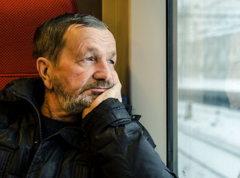 Close-up of thoughtful man traveling in train during winter