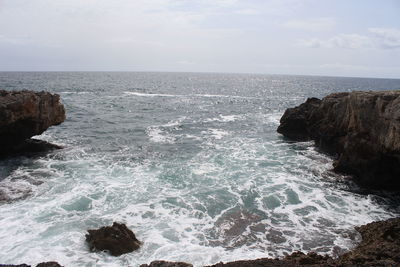 Scenic view of rocks in sea against sky