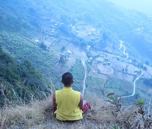 Rear view of boy sitting on landscape