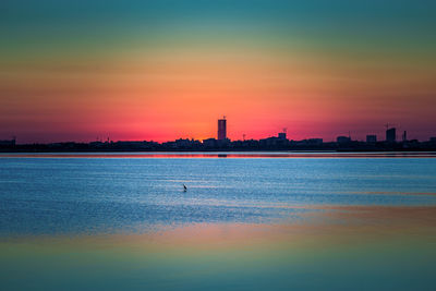 Sea and buildings against sky during sunset