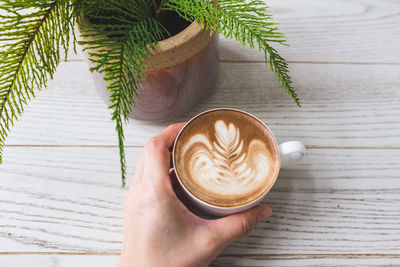 Cropped image of hand holding coffee cup on table