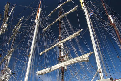 Low angle view of ship masts in harbor against clear blue sky