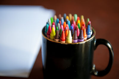 Close-up of crayons in mug on table