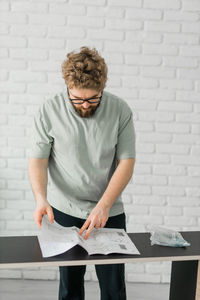 Side view of man using laptop while standing against wall