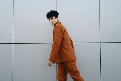 Portrait of young woman standing against wall