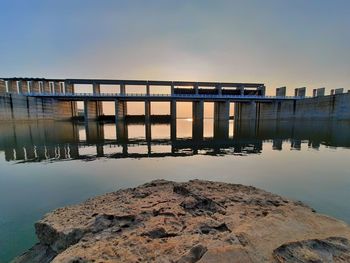 Bridge over river against sky during sunset