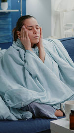 Young woman sitting on bed at home