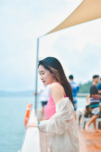 Portrait of young woman standing against sea