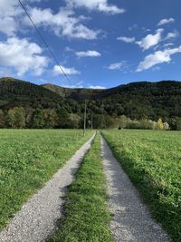 Surface level of road amidst field against sky