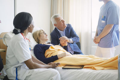 Couple looking at medical professionals in hospital ward