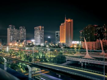 Illuminated modern buildings in city against sky at night