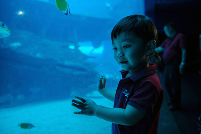 Close-up of boy using mobile phone in aquarium