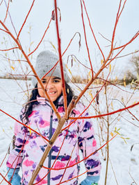 Portrait of young woman standing on snow covered field