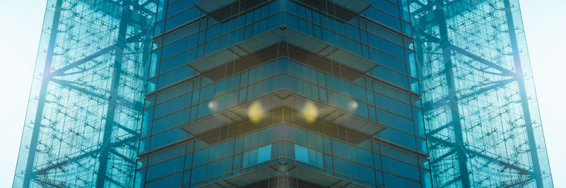 Low angle view of glass building against clear blue sky