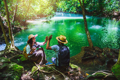 Rear view of people sitting by plants in forest