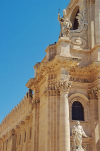 Low angle view of statues on building against clear sky