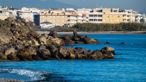 Rocks on beach by buildings in city