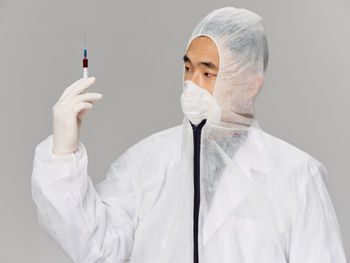 Side view of woman holding syringe against white background